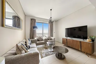 a living room with couches and a flat screen tv at Luxurious 2BR Apartment in Sobha Hartland Greens in Dubai