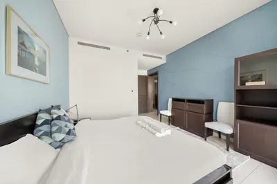 a bedroom with a white bed and a blue wall at Luxurious 2BR Apartment in Sobha Hartland Greens in Dubai