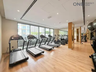 a gym with a row of treadmills at Luxurious 2BR Apartment in Sobha Hartland Greens in Dubai