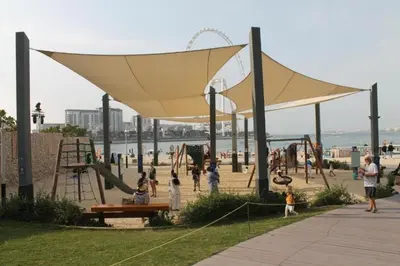 a group of children playing on a playground at the beach at The Dorra Bay Offers Stunning 2bedroom Duplex JBR Sea View Marina Canal view in Dubai