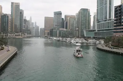 a boat in a river in a city with buildings at The Dorra Bay Offers Stunning 2bedroom Duplex JBR Sea View Marina Canal view in Dubai