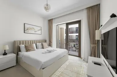 a white bedroom with a bed and a balcony at Stylish 2BR at Creek Grove Near Downtown in Dubai
