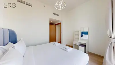 a white bedroom with a white bed and a mirror at Cozy and Modern 1BR for 2 in Dubai