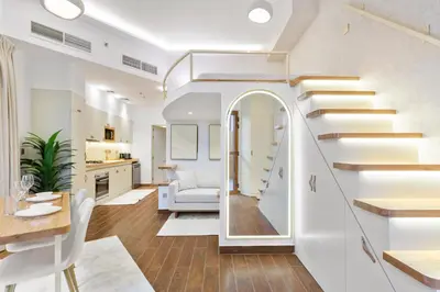 a living room with stairs and a dining room at Designer Loft Studio with top Amenities in JVC in Dubai