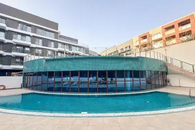 a building with a swimming pool in front of a building at Designer Loft Studio with top Amenities in JVC in Dubai