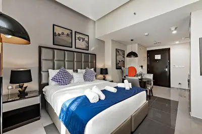 a bedroom with a large bed with a blue blanket at Studio with a Large Terrace at DAMAC Majestine in Dubai