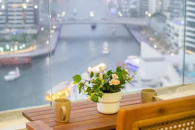 a vase with flowers sitting on a table in front of a window at Luxury 3BHK in Dubai Marina DEC 1307 in Dubai