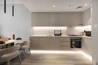a kitchen with wooden cabinets and a table with chairs at Luxury 1 BHK in Jumeirah Village Circle BydPie Concept 302 in Dubai