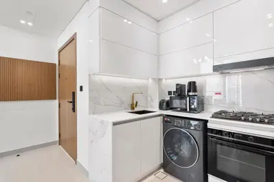 a white kitchen with a washer and a stove at Charming 1Bedroom in Binghatti Gardenia in Dubai