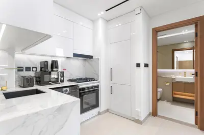 a white kitchen with white appliances and a sink at Charming 1Bedroom in Binghatti Gardenia in Dubai