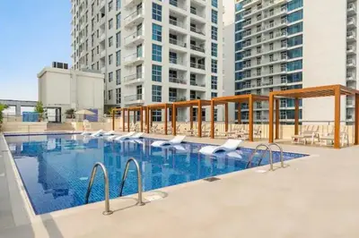 a swimming pool with chairs and buildings in the background at Luxury 3BHK in Dubai Marina DEC 702 in Dubai