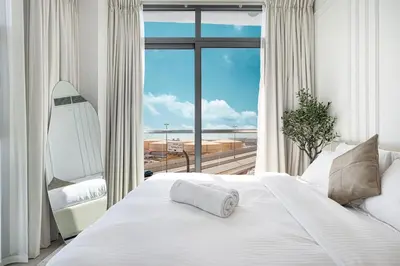 a bedroom with a white bed and a large window at Luxury 3BHK in Dubai Marina DEC 702 in Dubai