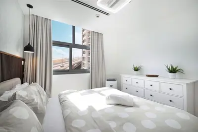 a white bedroom with a bed and a window at Luxury 3BHK in Dubai Marine By dPie DEC 903 in Dubai