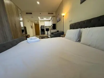 a bedroom with a large bed with white sheets at Furnished Studio in JVC Hassle-Free Living in Dubai