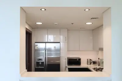 a kitchen with white cabinets and a stainless steel refrigerator at Prime Located 2BR Near Burj Khalifa & Dubai Mall in Dubai