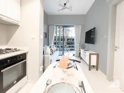 a kitchen and living room with a table and a stove at Wonderful Stay at Zada Tower l 1BR with Balcony in Dubai