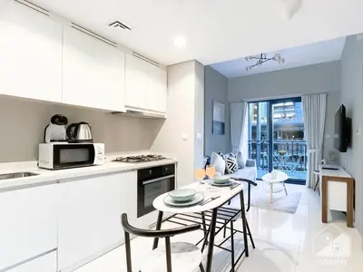 a kitchen and living room with a table and chairs at Wonderful Stay at Zada Tower l 1BR with Balcony in Dubai
