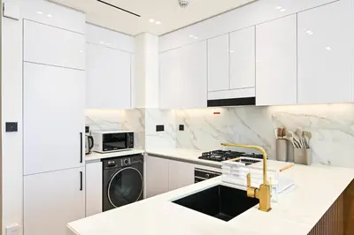 a white kitchen with a sink and a dishwasher at Golden Stays - Binghatti Amber I Luxury 1BR Apartment I Fully Furnished I Pool & Gym in Dubai
