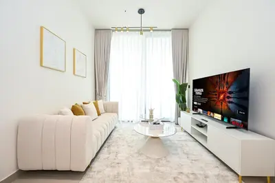 a white living room with a white couch and a tv at Golden Stays - Binghatti Amber I Luxury 1BR Apartment I Fully Furnished I Pool & Gym in Dubai
