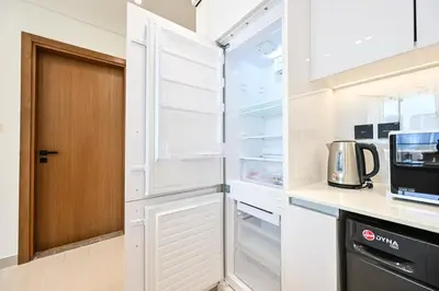 a kitchen with white cabinets and a refrigerator at Golden Stays - Binghatti Amber I Modern 1BR Apartment I Balcony, Pool & Gym Access in Dubai