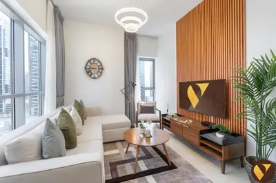 a living room with a white couch and a tv at Vogue Downtown Bellevue Towers near Burj Khalifa and Dubai Mall, One Bedroom Apartment with City View, Full Access to all Amenities in Dubai