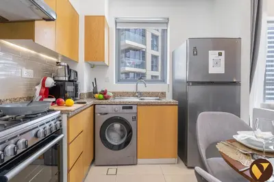 a kitchen with a washing machine and a sink at Vogue Downtown Bellevue Towers near Burj Khalifa and Dubai Mall, One Bedroom Apartment with City View, Full Access to all Amenities in Dubai