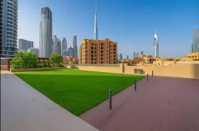 a green lawn in a city with tall buildings at Vogue Downtown Bellevue Towers near Burj Khalifa and Dubai Mall, One Bedroom Apartment with City View, Full Access to all Amenities in Dubai