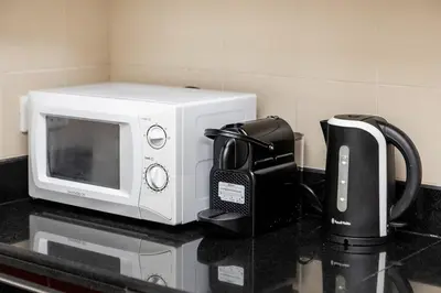 a white microwave sitting on a counter with a coffee maker at Lovely 1BR Apartment Bahar 6 JBR in Dubai