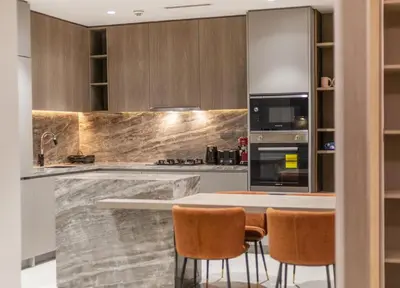 a kitchen with a marble counter top and wooden cabinets at Luxury 1 BHK in Dubai Marina JVC 904 in Dubai