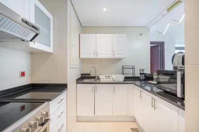a kitchen with white cabinets and black counter tops at Luxury 2BHK in Jumeirah Late Towers JLT 2609 in Dubai