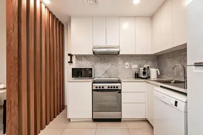 a kitchen with white cabinets and a stove top oven at Modern 1BR Apartment Lamtara 3 in MJL in Dubai