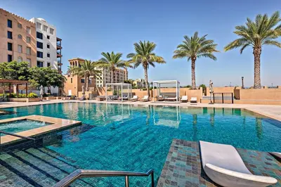 a large swimming pool with chairs and palm trees at Modern 1BR Apartment Lamtara 3 in MJL in Dubai