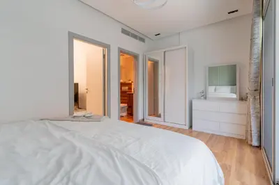 a white bedroom with a large bed and a bathroom at Dubai Marina - 1BHK Modernistic Apartment in Dubai