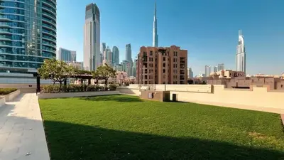 a park with green grass in a city with buildings at Vogue Downtown Bellevue Towers near Burj Khalifa and Dubai Mall, One Bedroom Apartment with Balcony and City View, Full Access to all Amenities in Dubai