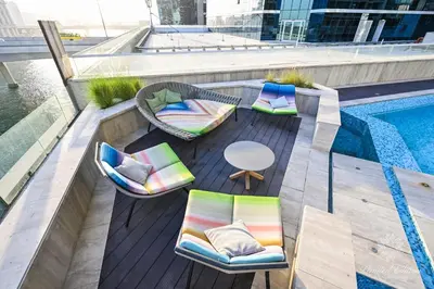 a balcony with chairs and a table and a pool at Luxury Apartments - Urban Oasis by Missoni - Business Bay - Canal View - 10 Minutes from Dubai Mall Burj Khalifa in Dubai
