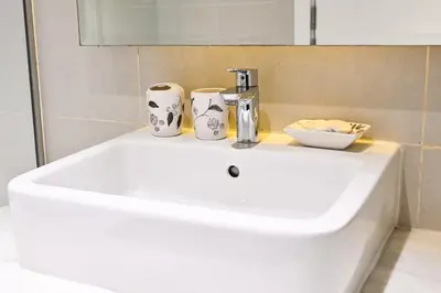a white sink with two cups on top of it at Canal View Studio near Dubai Mall in Dubai