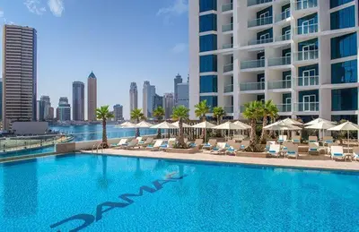 a large swimming pool with chairs and umbrellas and a building at Canal View Studio near Dubai Mall in Dubai