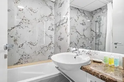 a white bathroom with a sink and a shower at Luxury 4BR w Marina Views Near Beach & Mall in Dubai