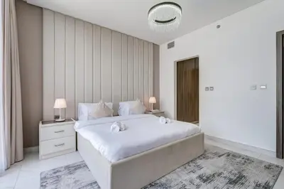 a white bedroom with a large bed and a window at PVH - Lagoon View 1BR - District One in Dubai