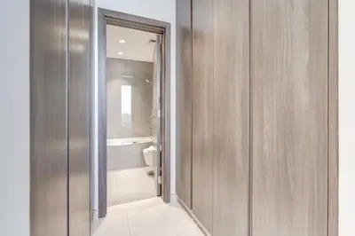 a bathroom with a toilet and a sliding glass door at PVH - Lagoon View 1BR - District One in Dubai