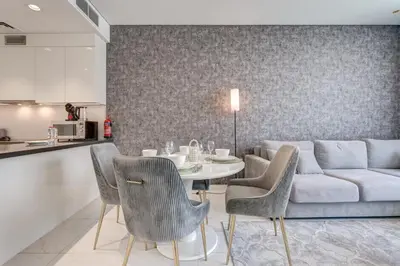a living room with a couch and a table and chairs at PVH - Lagoon View 1BR - District One in Dubai