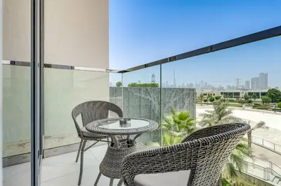 a patio with two chairs and a table on a balcony at PVH - Lagoon View 1BR - District One in Dubai