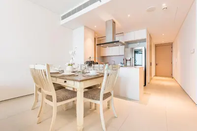 a kitchen and dining room with a wooden table and chairs at 3BR Overlooking Sea, Ain Dubai, and Bluewaters Island, Walking Distance to the Beach, The Address Residences, Jumeirah Beach Residence by Deluxe Holiday Homes in Dubai