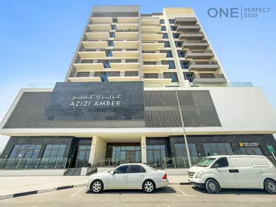 two cars parked in a parking lot in front of a building at Modern 1-Bedroom Apartment in Al Furjan With Pool & Gym in Dubai