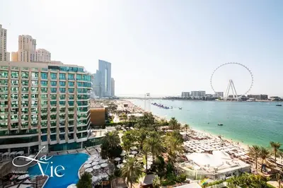 a view of a beach with a ferris wheel in the background at La Vie, JBR - Exclusive Beach & Pool Access in Dubai