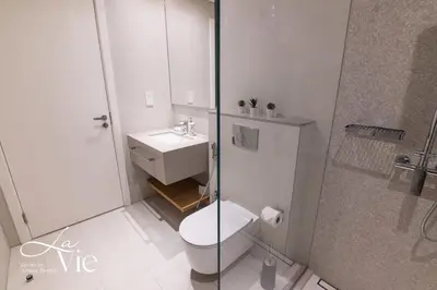 a white bathroom with a toilet and a shower at La Vie, JBR - Exclusive Beach & Pool Access in Dubai