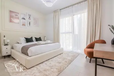 a white bedroom with a large bed and a desk at La Vie, JBR - Exclusive Beach & Pool Access in Dubai
