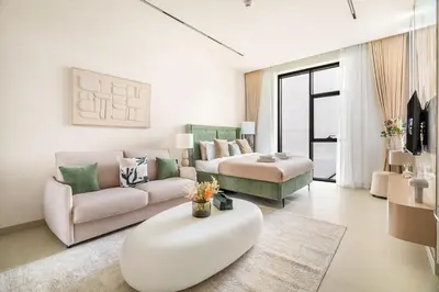 a living room with a couch and a table at New! Stylish Studio with Pool, Gym & Jacuzzi, JVC in Dubai