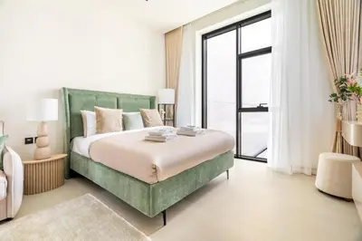 a bedroom with a green bed and a large window at New! Stylish Studio with Pool, Gym & Jacuzzi, JVC in Dubai
