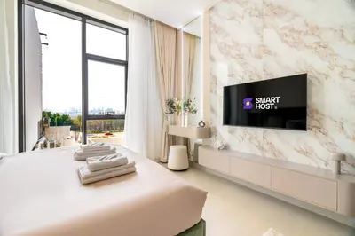 a bedroom with a bed and a tv on a wall at New! Stylish Studio with Pool, Gym & Jacuzzi, JVC in Dubai